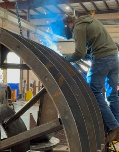 Welder fabricating custom industrial fan housing in workshop
